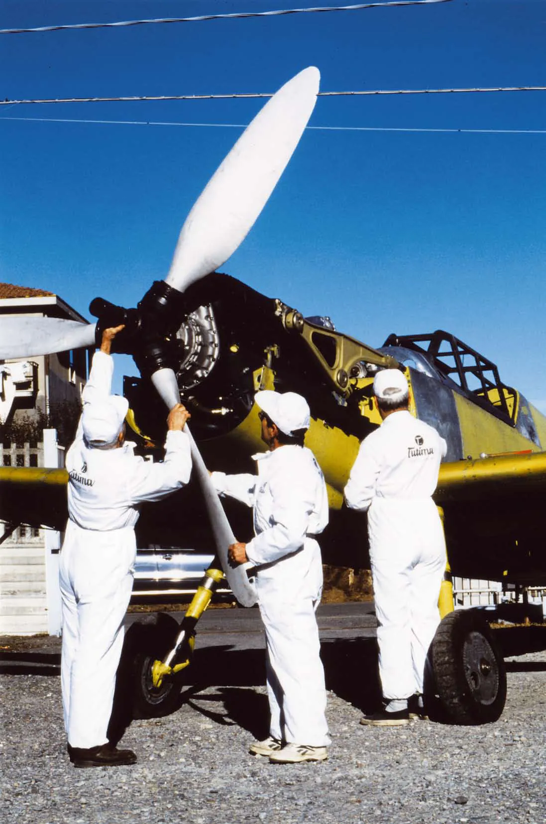 Tutima aviation crew beside propeller aircraft