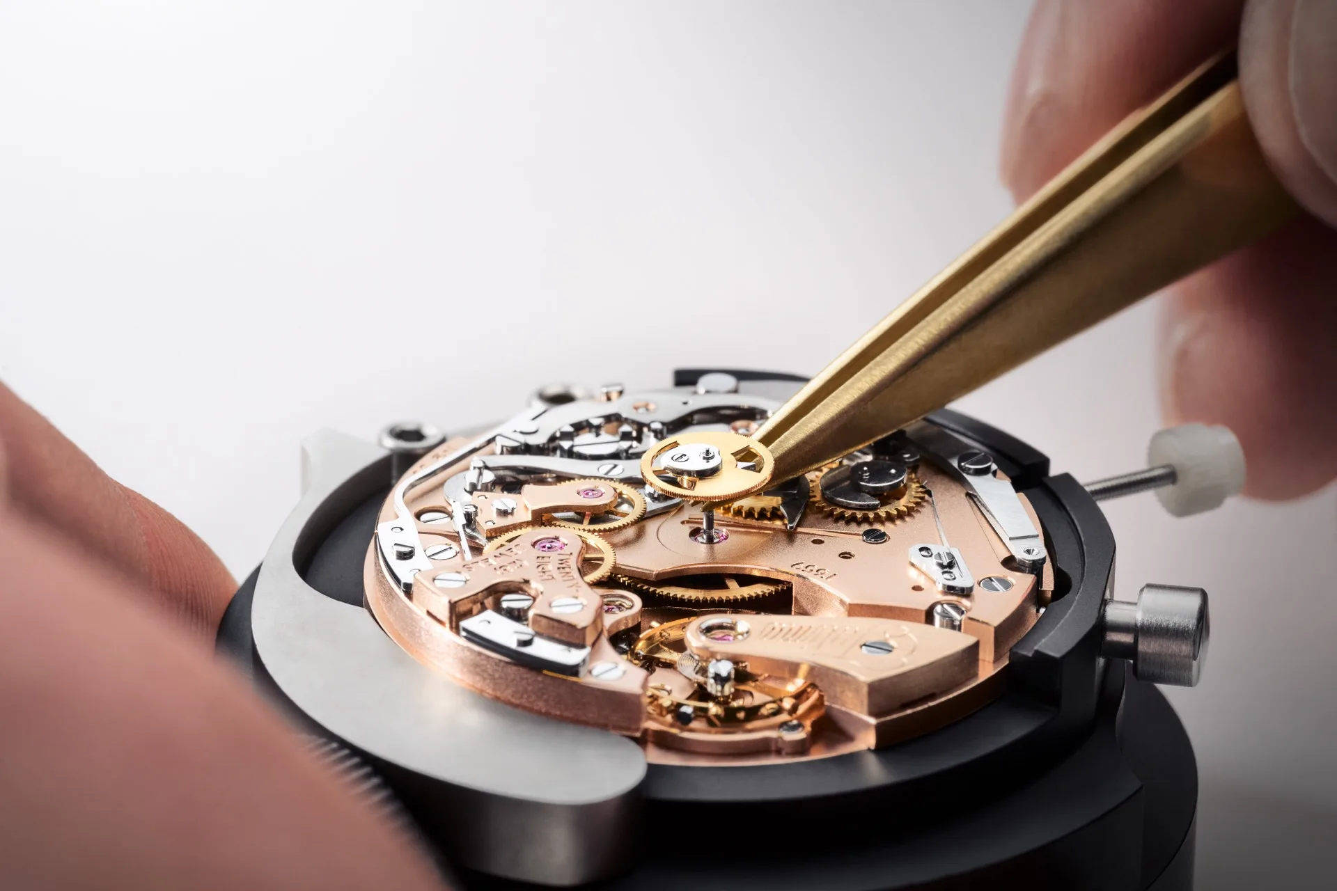 Watchmaker adjusting a Tutima manufacture movement with brass tweezers