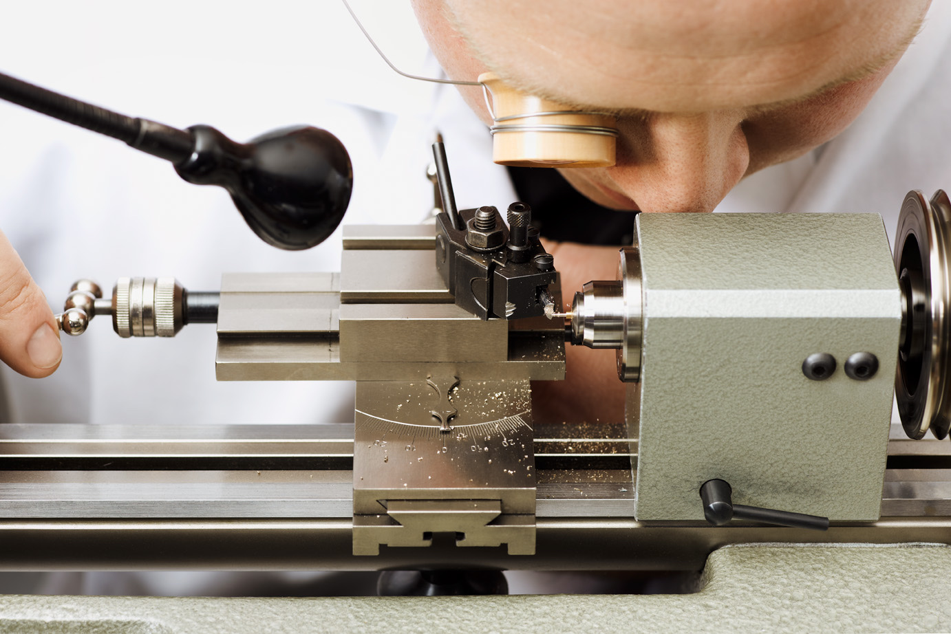Watchmaker at lathe — close-up, concentration
