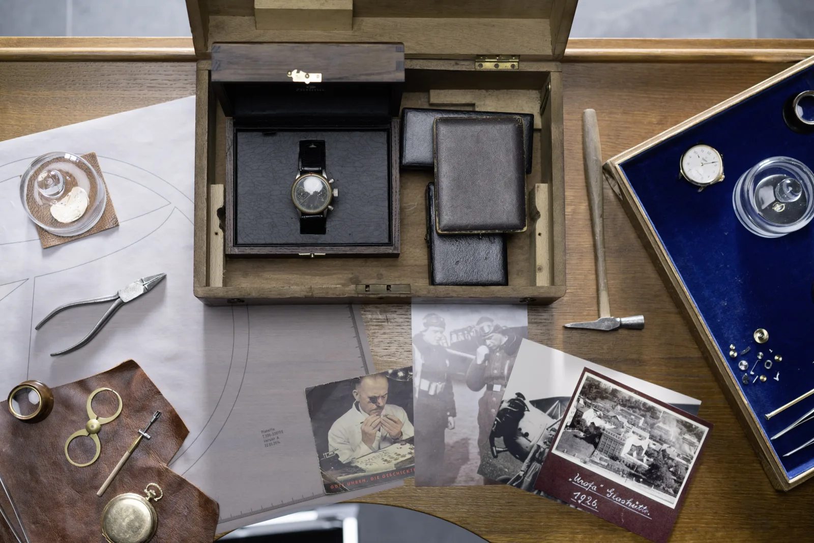 UROFA 1926 postcard, Garantieschein, and Flieger chronograph on vintage desk — physical proof of the founding story